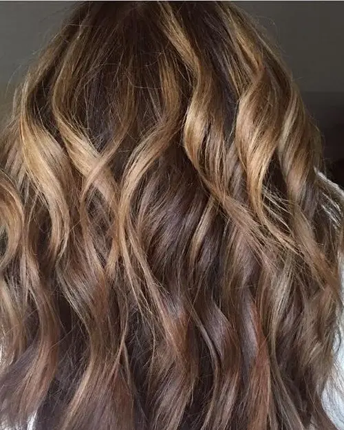 Dimensional brunette highlights styled in soft waves at Freddie Rose Salon